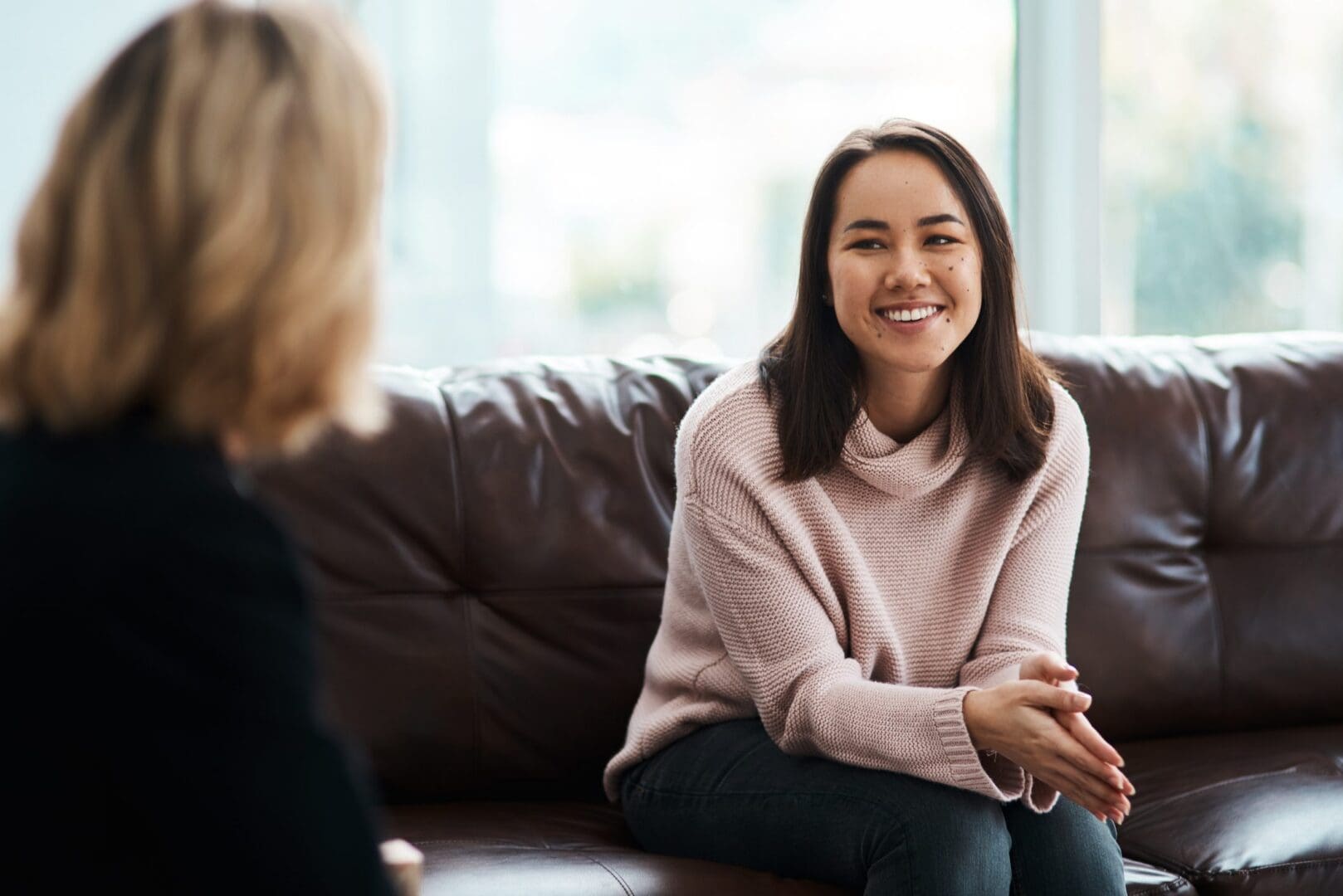 Two women engaged in a friendly conversation on a couch.